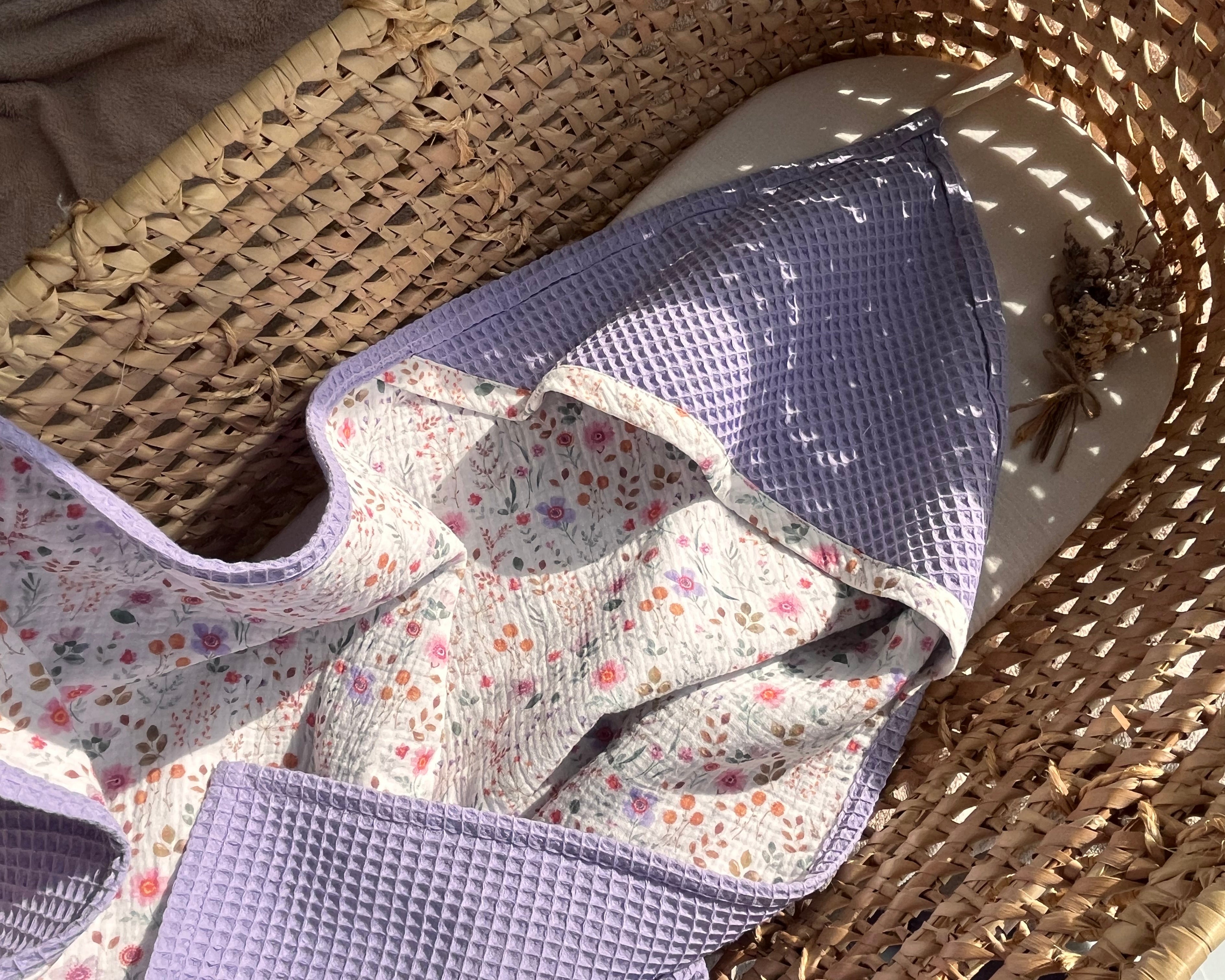 Floral-patterned baby hooded towel on a woven surface