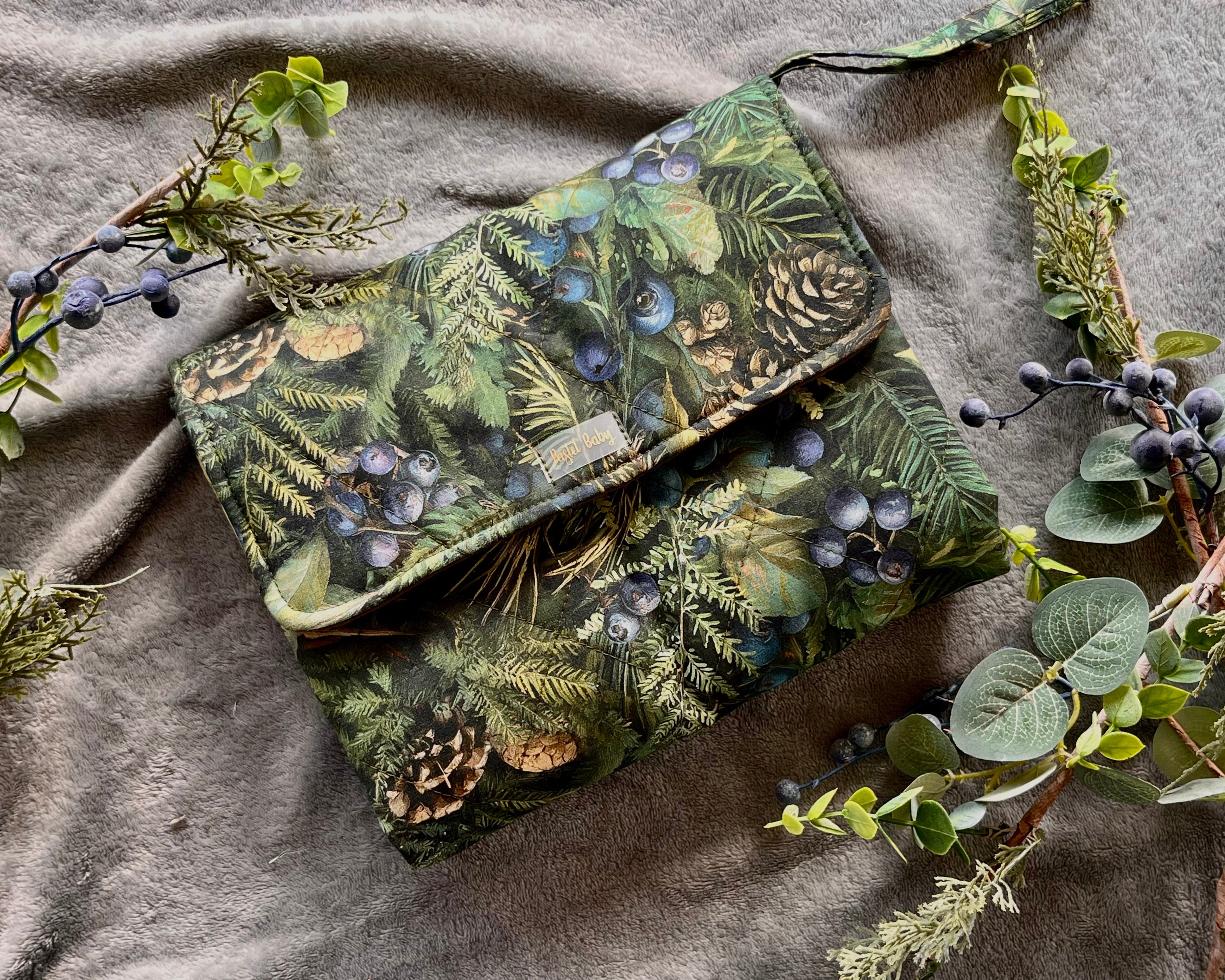 Green patterned pouch with nature-themed design on a textured fabric background