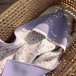 Floral-patterned baby hooded towel on a woven surface