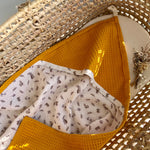 Mustard yellow textured fabric with a white patterned fabric inside a woven basket.