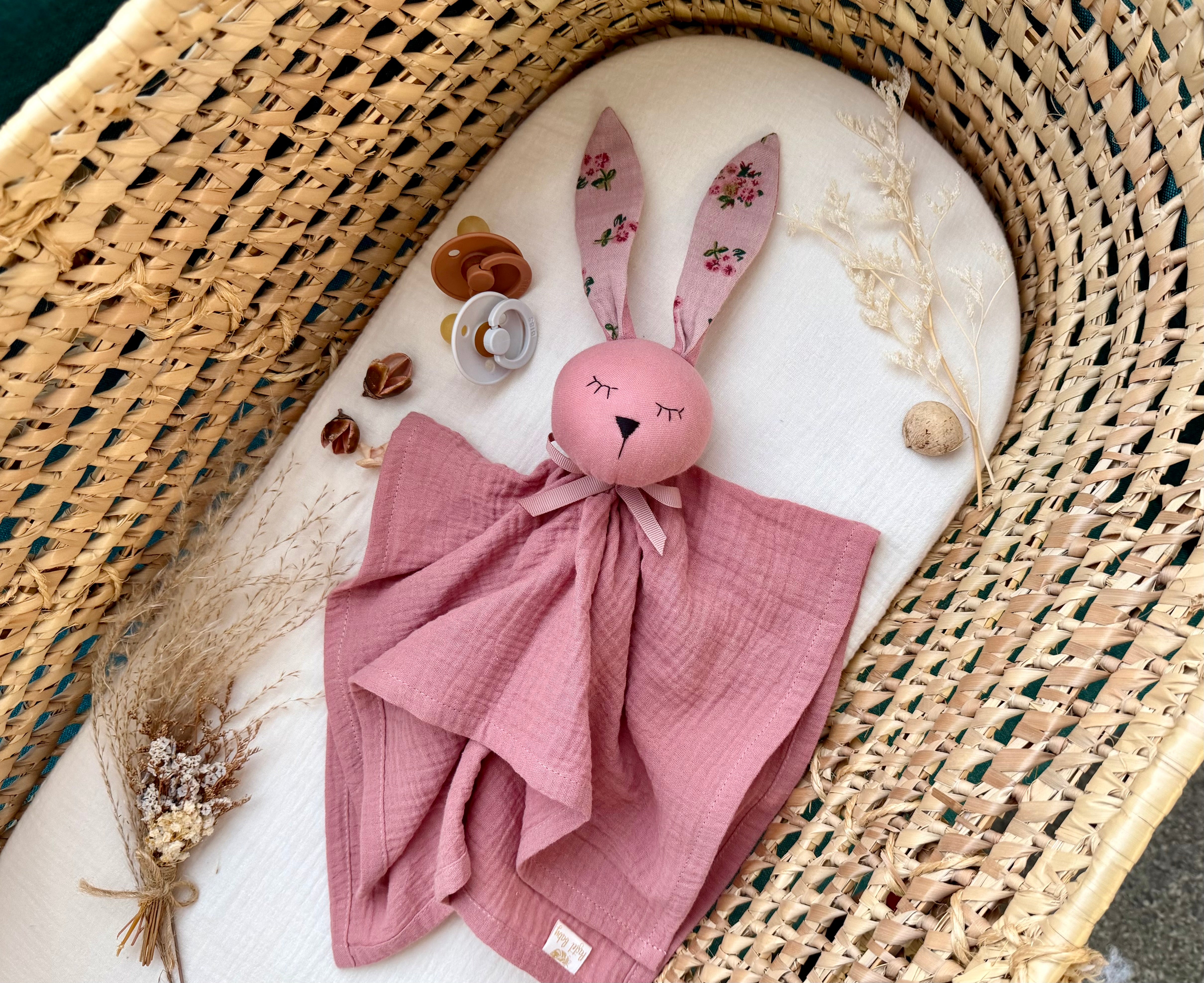Pink plush toy with bunny ears on a white surface with a wicker basket in the background