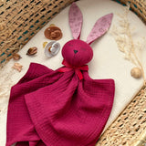 Maroon plush bunny toy with pink ears on a textured surface