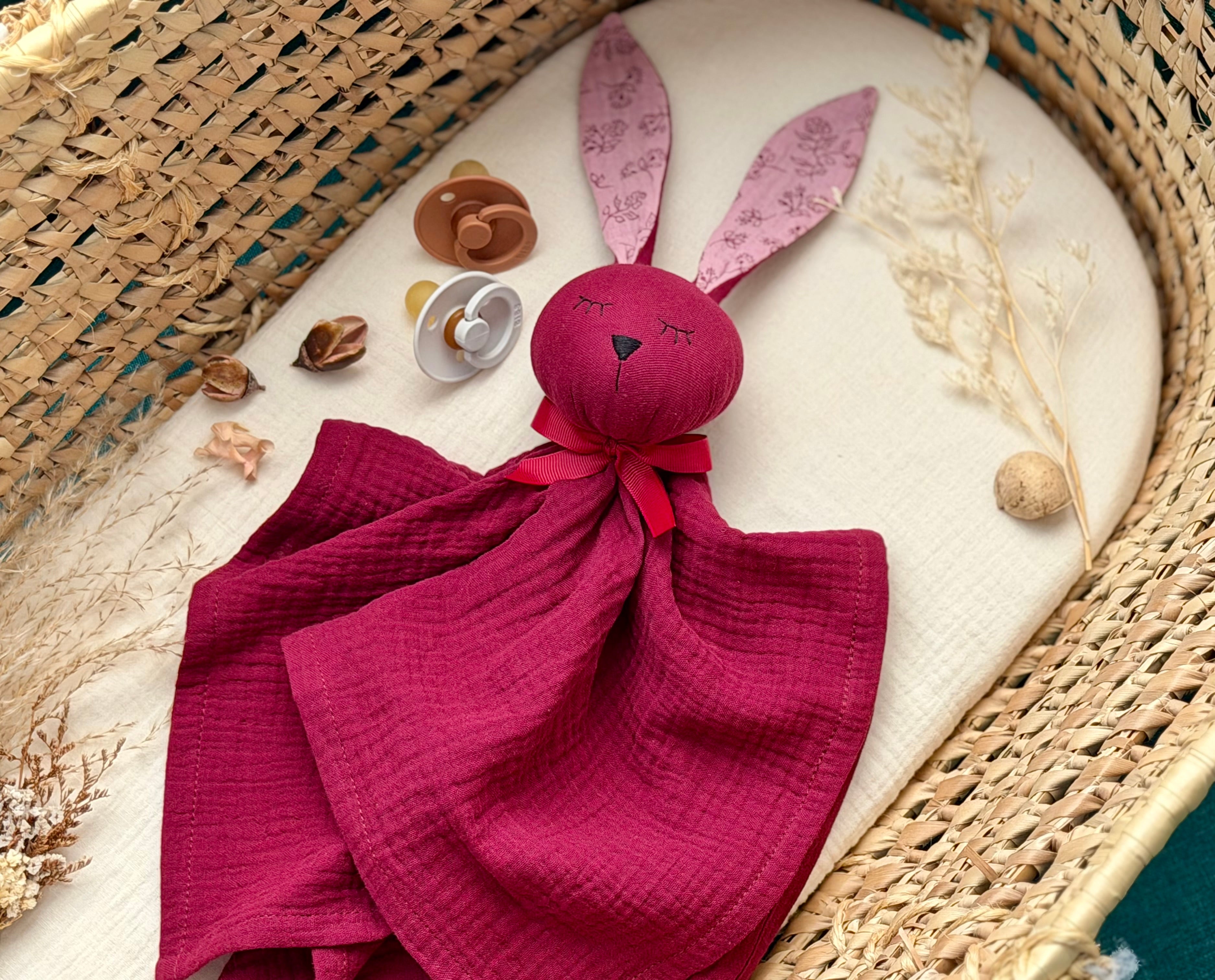 Maroon plush bunny toy with pink ears on a textured surface