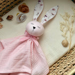 Pink bunny toy with floral ears on a textured surface