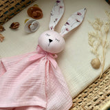 Pink bunny toy with floral ears on a textured surface
