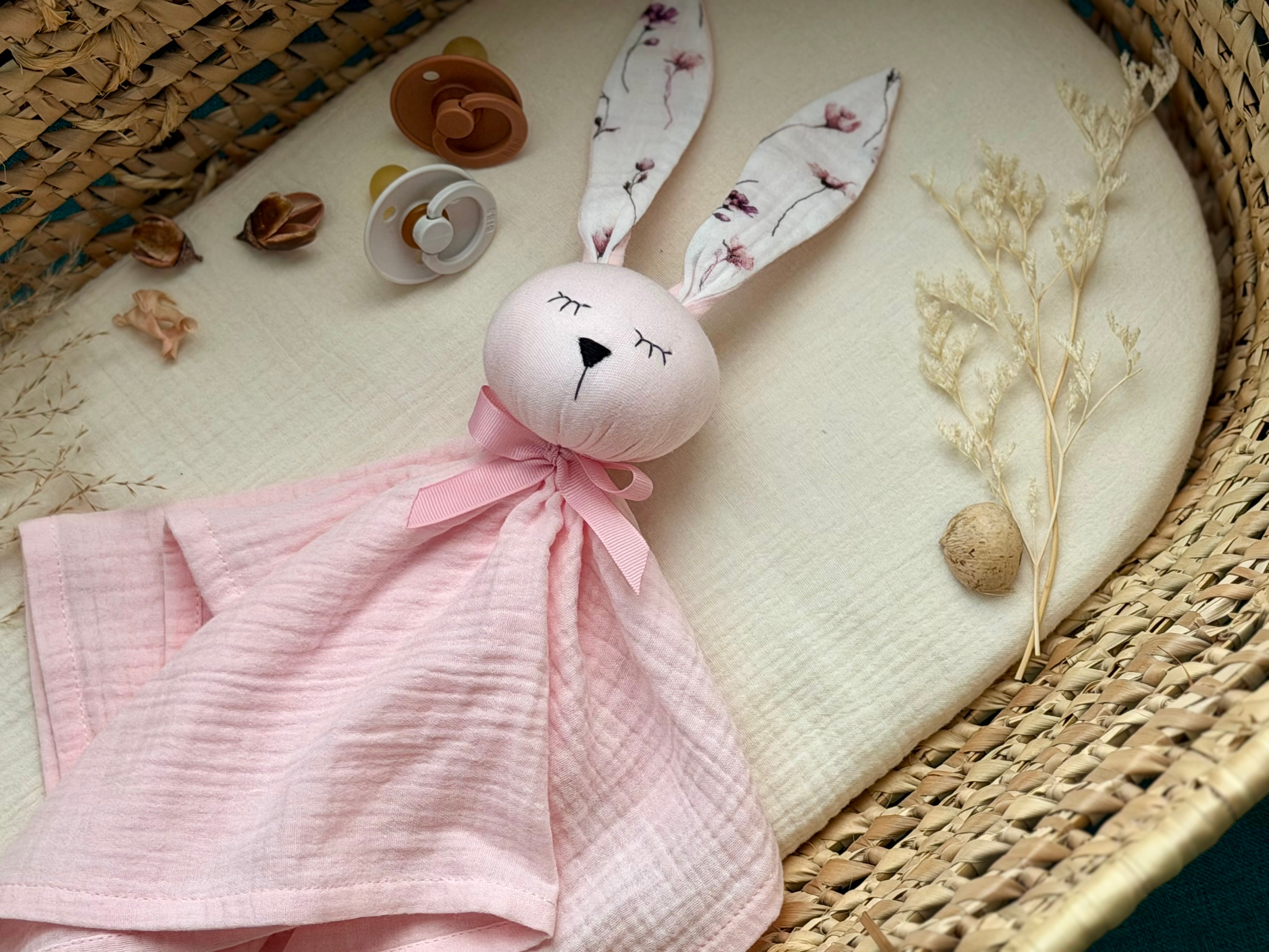 Pink bunny toy with floral ears on a textured surface